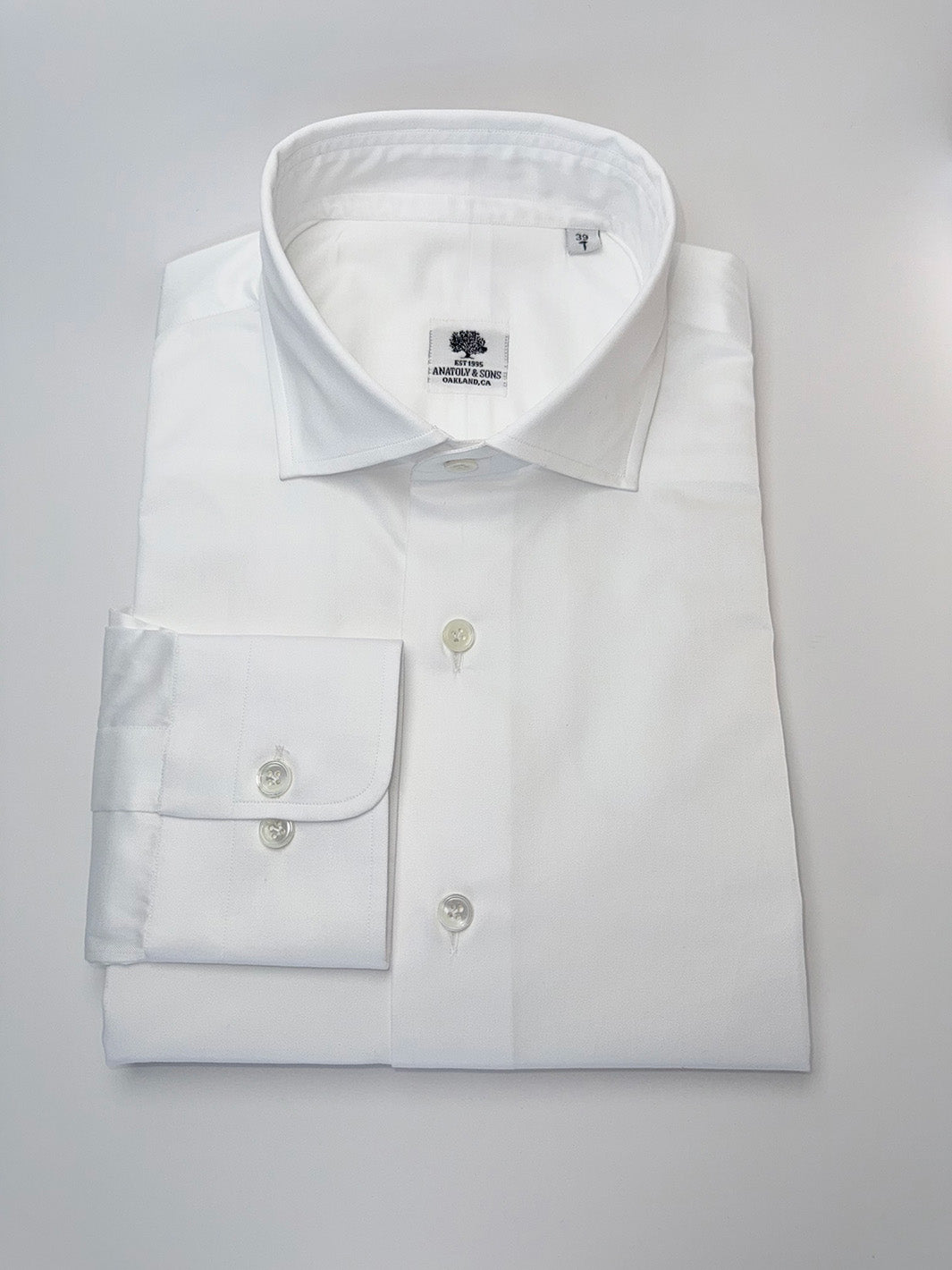 Folded white dress shirt with a collar on a light gray background