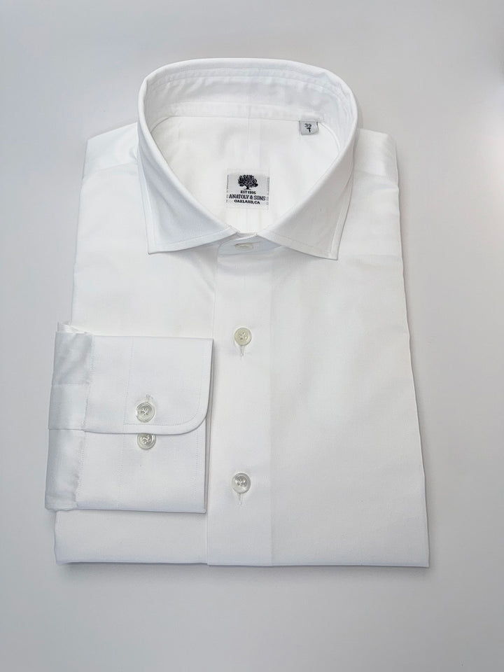 Folded white dress shirt with a collar on a light gray background