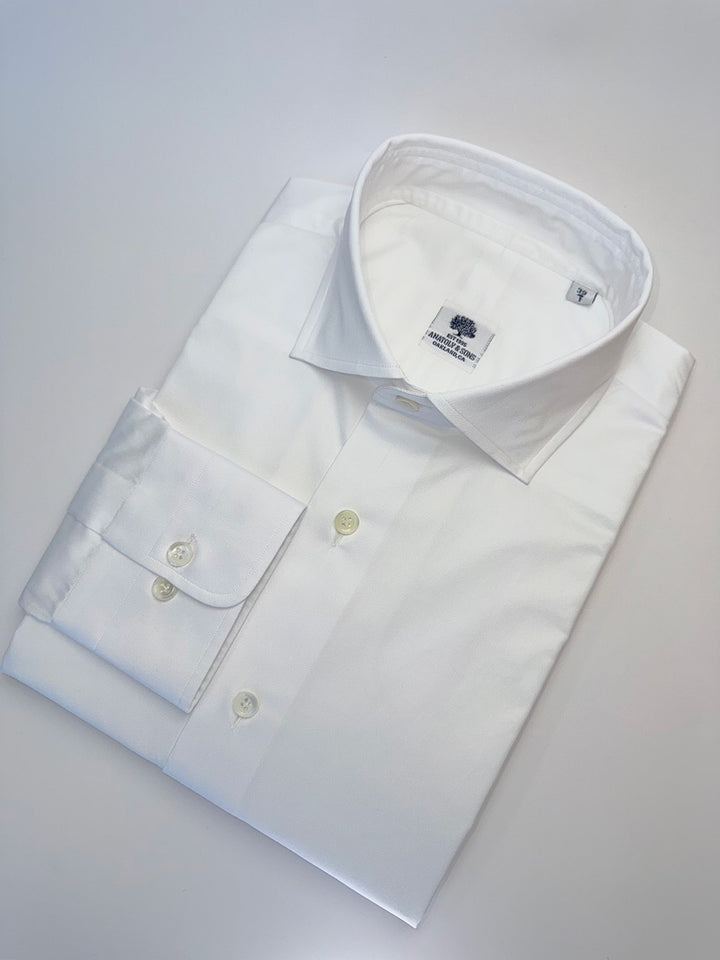 Folded white dress shirt with collar and buttons on a light gray background