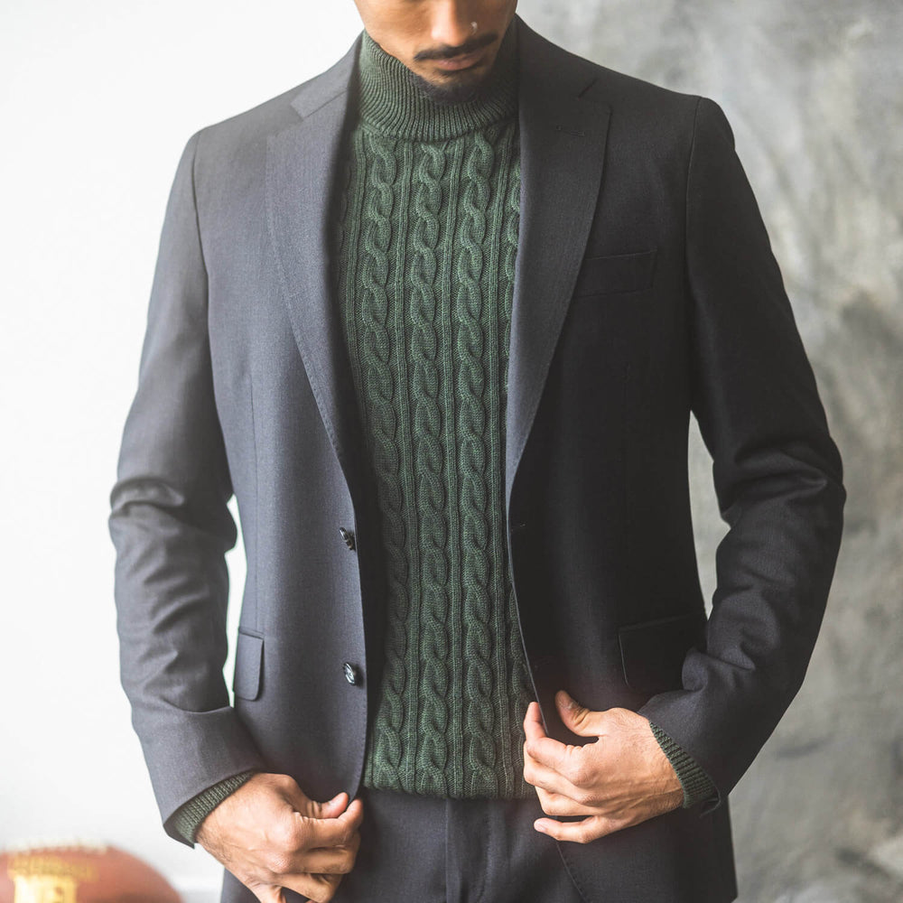 Closeup of man wearing Anatoly's charcoal Natural Stretch Suit over a green cable knit sweater